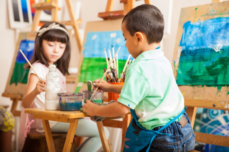 Um menino e uma menina pintam quadros de paisagem com tinta.