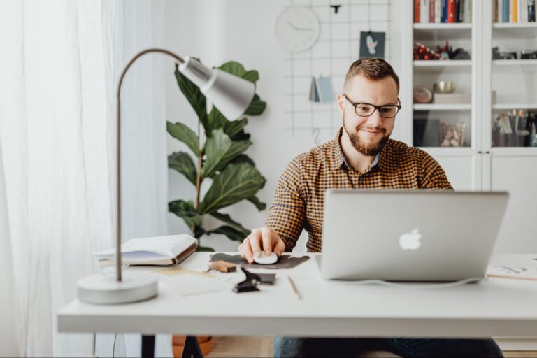 Um homem branco, de óculos e barba, está sentado mexendo em um notebook aprendendo sobre ambiente virtual de ensino.