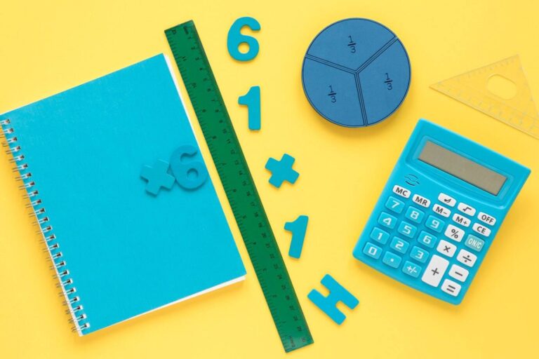 A imagem mostra diversos utensílios associados ao ensino de matemática - um caderno, uma régua, algumas letras e números soltos, uma calculadora, entre outros. 